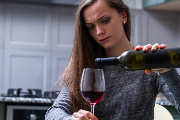 Depressed, divorced crying woman sitting alone in kitchen at hom