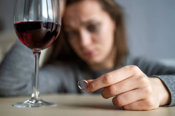 Crying, divorced woman holds a wedding ring in her hands and dri