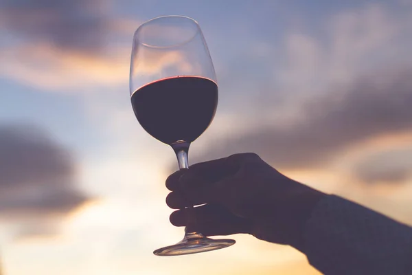 A glass wine in hand at sunset in the evening.