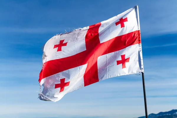 Georgian flag waving in the wind on the background of blue, clear sky