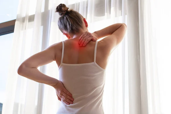 Young woman suffering from neck pain and backache, stretching the muscles at home. back and neck pain woman