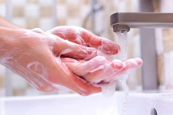 Hand hygiene. Person in the bathroom is cleaning and washing hands using soap foam