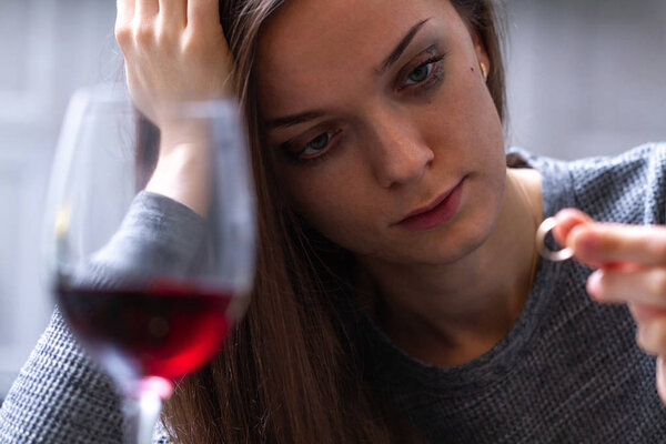 Плачущая, разведенная женщина держит и смотрит на обручальное кольцо и
