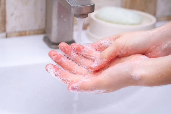 Hand hygiene. Person in the bathroom is cleaning and washing hands with soap.