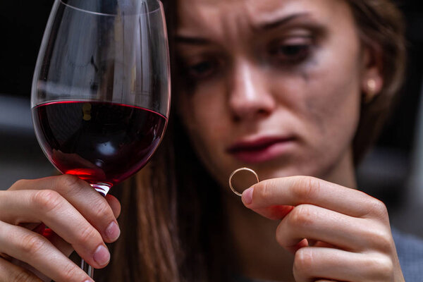 Плачущая, разведенная женщина держит и смотрит на обручальное кольцо и
