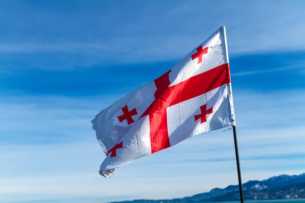 Georgian flag waving in the wind on the background of blue, clear sky