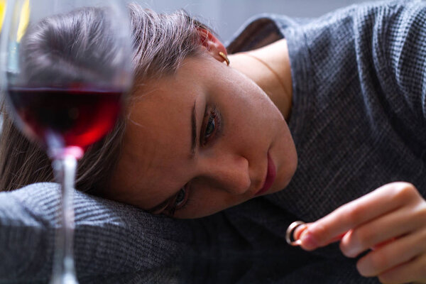 Плачущая, разведенная женщина держит и смотрит на обручальное кольцо и
