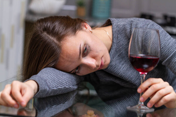 Depressed, divorced crying woman sitting alone in kitchen at hom