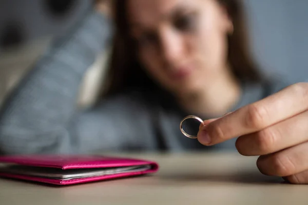 Divorced woman holds a wedding ring in her hands and crying beca — Stock Photo, Image