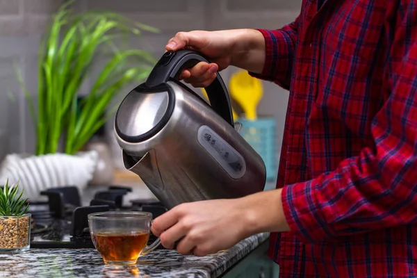 人は自宅の台所で電気ポットから熱湯を使用してお茶を作る 朝食の時間 — ストック写真