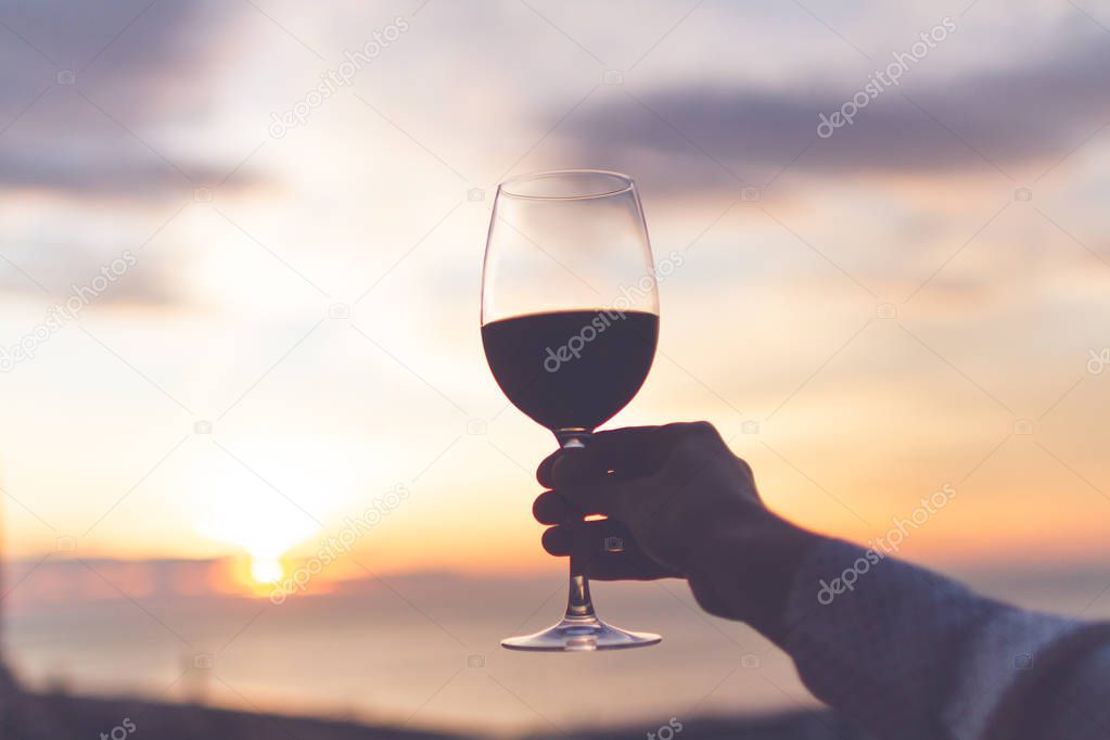 A glass wine in hand at sunset in the evening. 