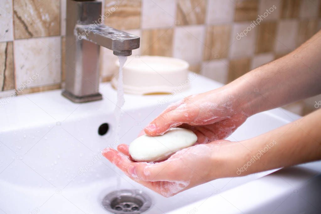 Hand hygiene. Person in the bathroom is cleaning and washing hands with soap.