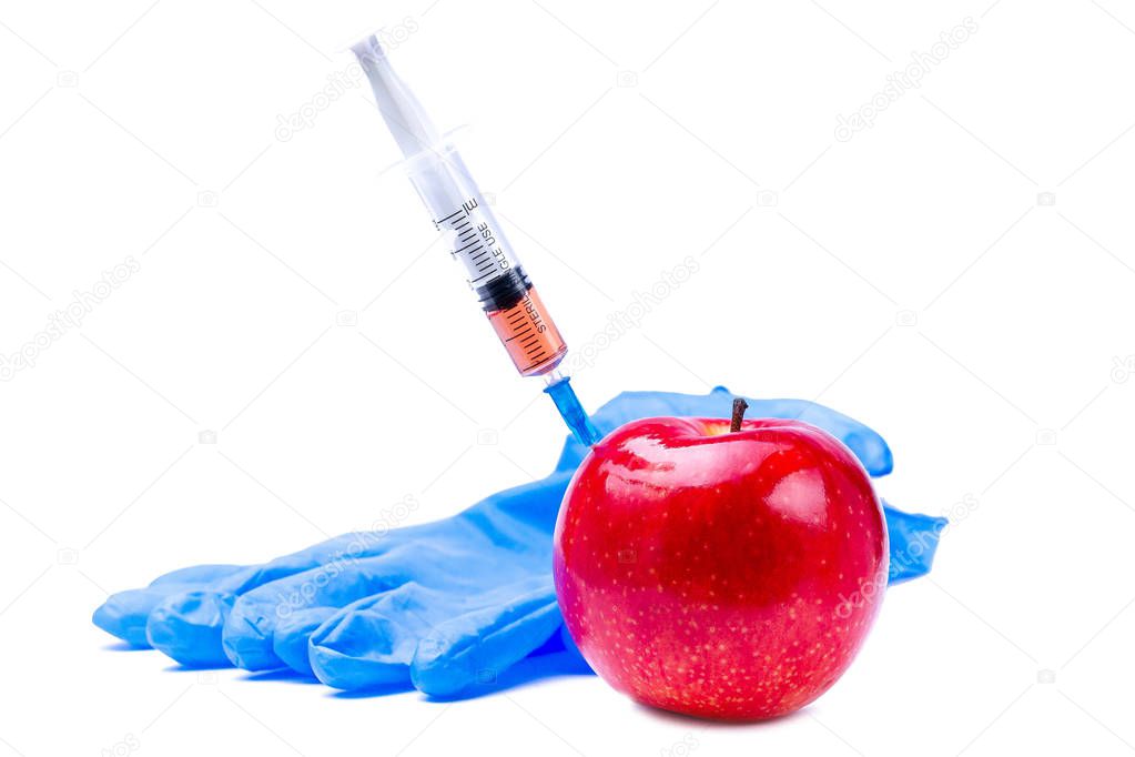 Pesticides and nitrates are injected into a red apple with a syringe. Gmo concept and genetically modified organism. Gmo free and natural fruits without chemical additives.