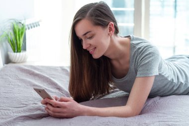 Genç, çekici, bekar bir kadın. Sohbet etmek için akıllı telefon kullanıyor. 