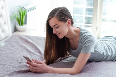 Genç, çekici, bekar bir kadın. Sohbet etmek için akıllı telefon kullanıyor. 