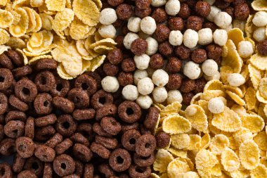 Doku ve kuru arka plan, çikolata, topları, halkalar ve sağlıklı tahıllar kahvaltı için sarı mısır gevreği. 