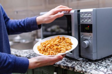 Using a microwave to warming a plate of homemade pilaf for lunch clipart