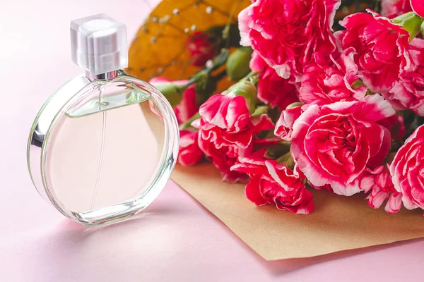 Una botella de perfume de mujer y un ramo de flores en un bac rosa — Foto de Stock