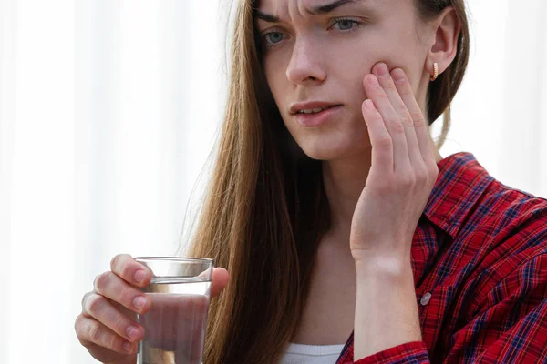 Young woman suffering and experiencing strong aching toothache.