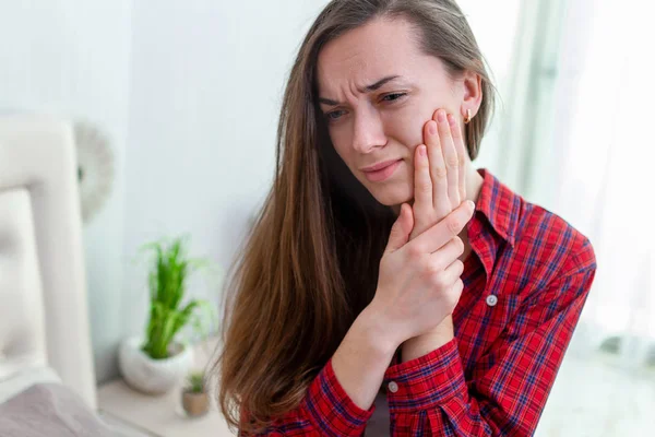 Young woman suffering and experiencing strong aching toothache.