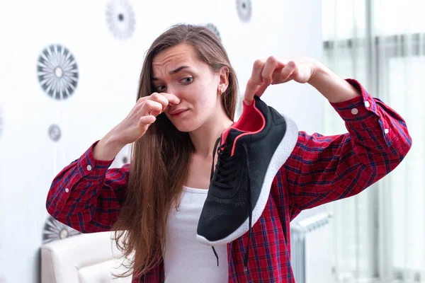 Woman is feeling unpleasant smell from sweaty running shoes afte