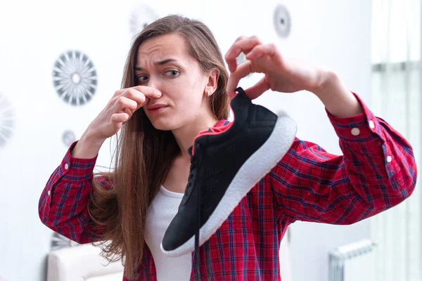 Woman is feeling unpleasant smell from sweaty running shoes afte