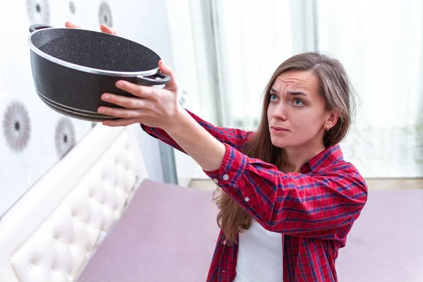 Mujer joven preocupada, agitada, estresada sosteniendo la sartén durante el leaka — Foto de Stock