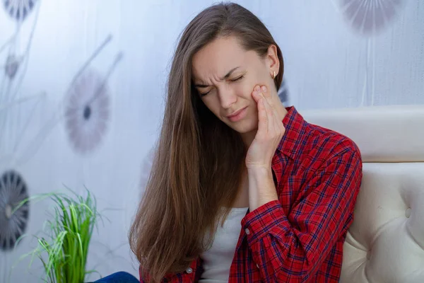 Young woman suffering and experiencing strong aching toothache.