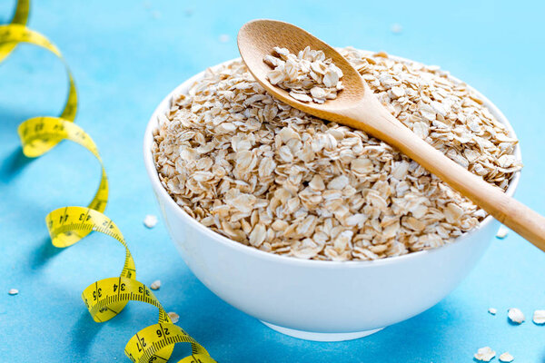 Диетическая концепция. Чаша с овсянкой и ложка с желтой измерительной лентой
 