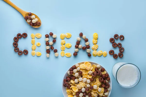 Cereals bowl, spoon and a glass of milk on a blue background. Gl — Stock Photo, Image