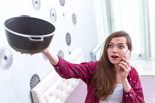 Worried, agitated, stressed young woman holding pan and calling — Stock Photo, Image