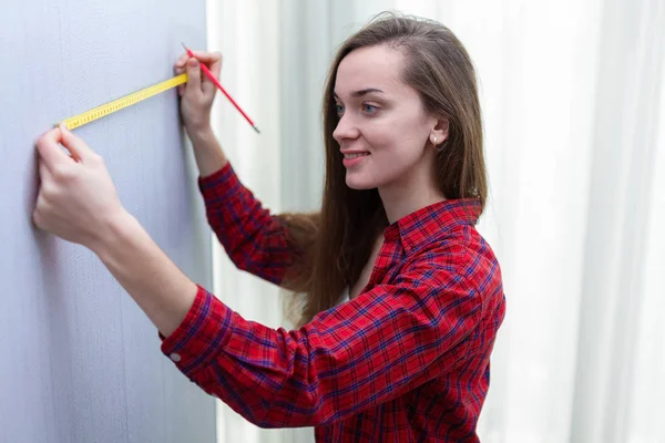 Mujer atractiva joven en camiseta está participando en reparaciones en el hogar un — Foto de Stock