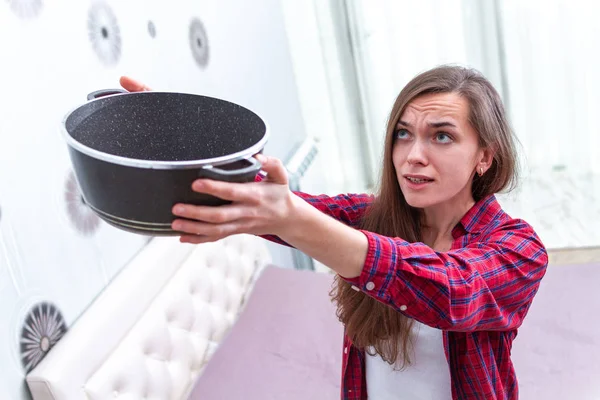 Беспокойная, взволнованная, напряженная молодая женщина держит сковородку во время течки — стоковое фото