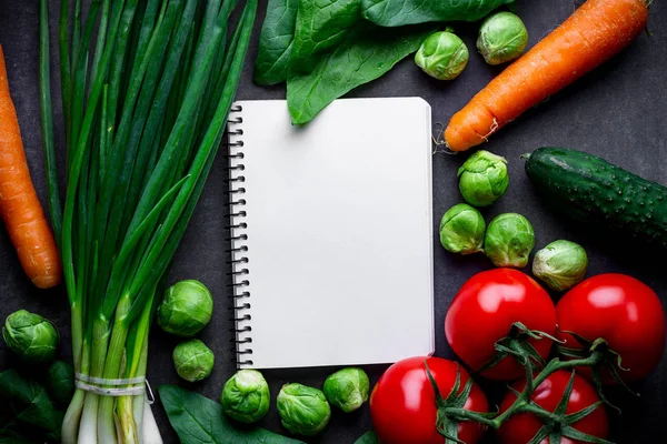 Ripe ingredients and blank recipe book for cooking fresh salad and vegetable dishes. Proper nutrition, healthy balanced food. Diet plan. Clean and healthy eating. Copy space