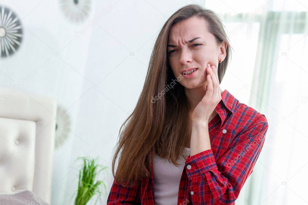 Young woman suffering and experiencing strong aching toothache. 