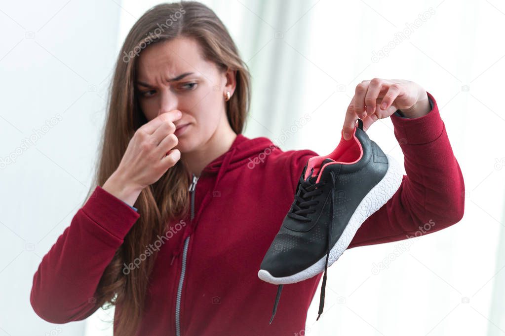 Woman is feeling unpleasant smell from sweaty running shoes afte