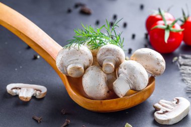 Ahşap kaşıkta dereotlu beyaz mantarlar. Ev yapımı domates, kiraz ve taze olgunlaşmış şampiyon.