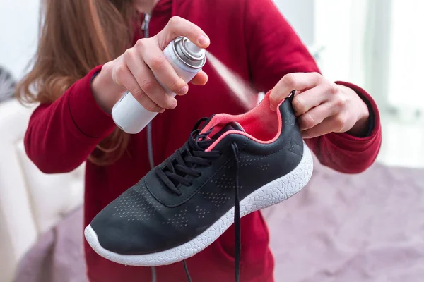 Een jonge vrouw die Deodorant spray op zweterige hardloopschoenen voor Eli — Stockfoto