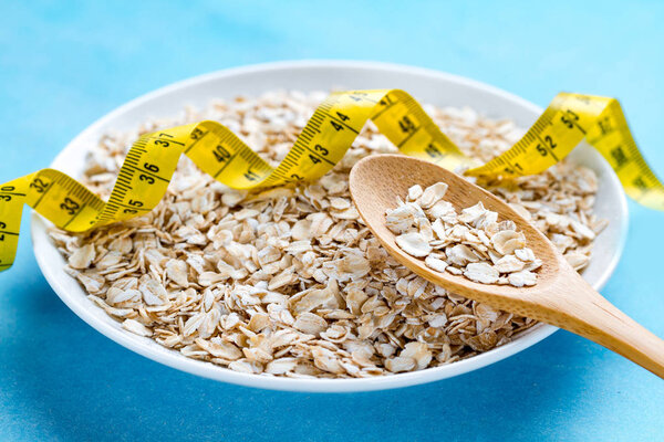 Диетическая концепция. Чаша с овсянкой и ложка с желтой измерительной лентой
 