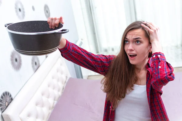 Worried, agitated, stressed young woman holding pan during leaka — Stock Photo, Image