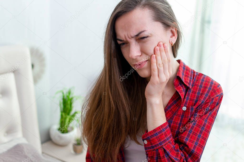 Young woman suffering and experiencing strong aching toothache. 
