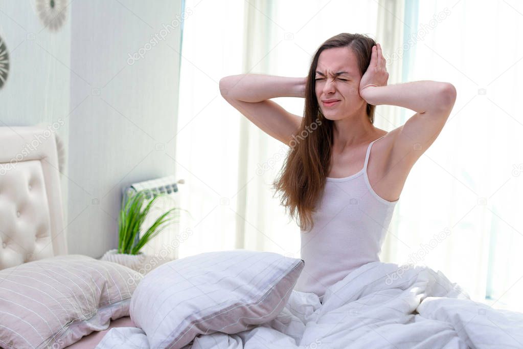 Young woman suffering and disturbed by noisy neighbors and cover