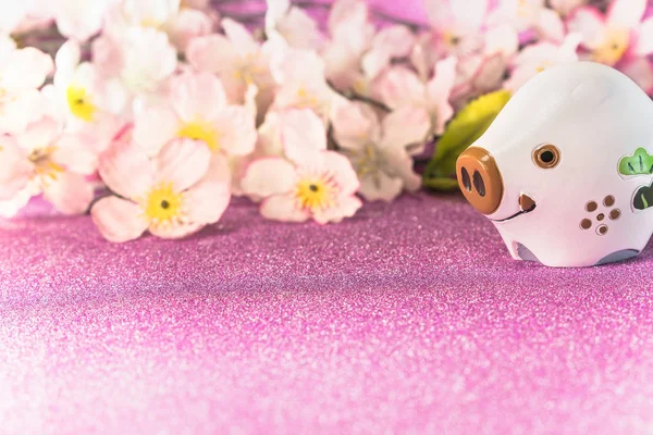 Pink glitter background with sakura cherry blossoms for japanese New Year's Cards with cute animal figurine of boar or pig.
