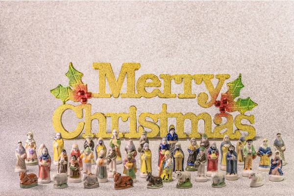 Small figurines of santons from French Provence used like beans of the cake of the kings during the Epiphany also called the Little Christmas with in back the golden word Merry Christmas.