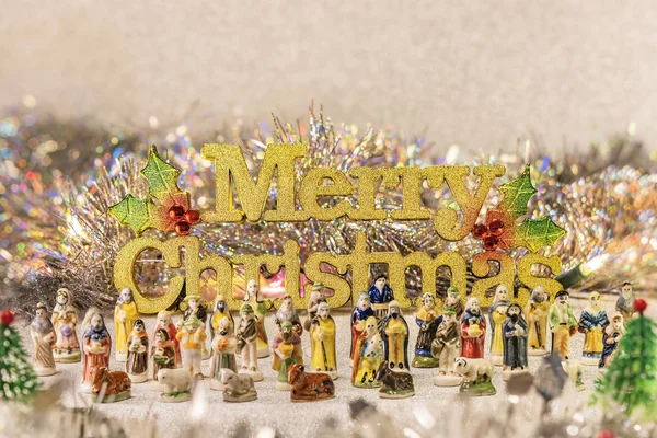 Small figurines of santons from French Provence used like beans of the cake of the kings during the Epiphany also called the Little Christmas with in back the golden word Merry Christmas.