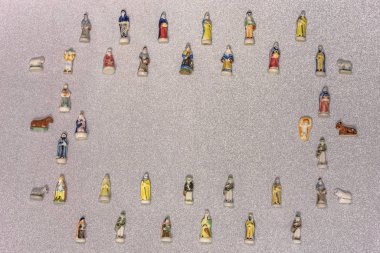Small figurines of santons from French Provence used like beans of the cake of the kings during the Epiphany also called the Little Christmas on a glitter silver snow background. clipart