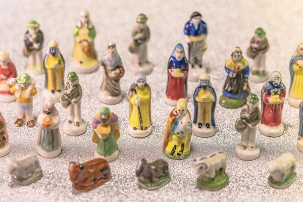 Small figurines of santons from French Provence used like beans of the cake of the kings during the Epiphany also called the Little Christmas on a glitter silver snow background.