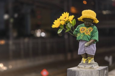 Tokyo, Japonya - 07 Temmuz 2018: Yakın çekim heykel peeing ve ayçiçeği çiçek hamamatsucho İstasyonu Tokyo, Japonya'da iskele üzerinde tutan küçük bir çocuk Manneken çiş.