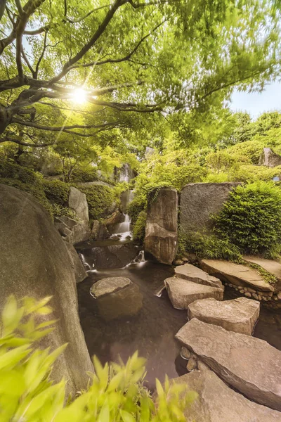 Waterfall of the Meijiro garden that flows into the central pond, which is crossed by a path of large flat stones under the foliage of the momiji through which the rays of the sun pass. The water plunges four meters, raising a spray. Three tons of wa