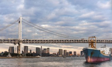 Kargo gemisi Odaiba Körfezi 'nden Tokyo' daki Odaiba Körfezi 'nin Gökkuşağı Köprüsü' nün altından geçiyor..